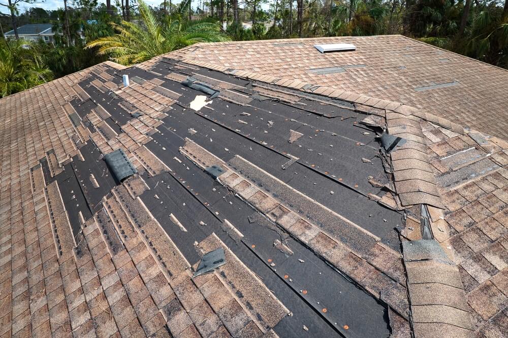A gable roof experiencing wind damage during a storm.