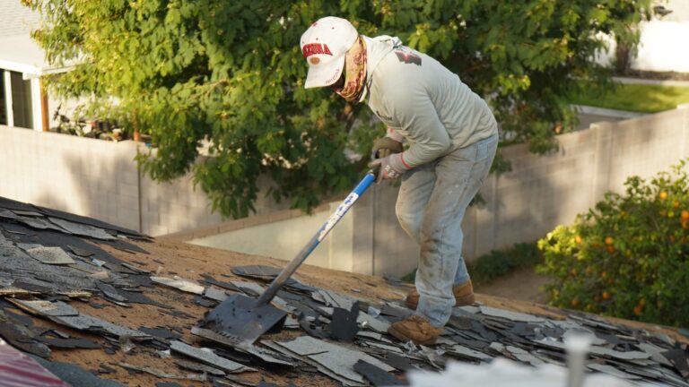 Roofer tearing off old asphalt shingles