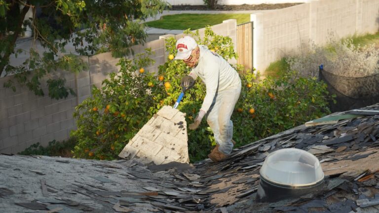 Roofer stripping worn shingles down to the deck