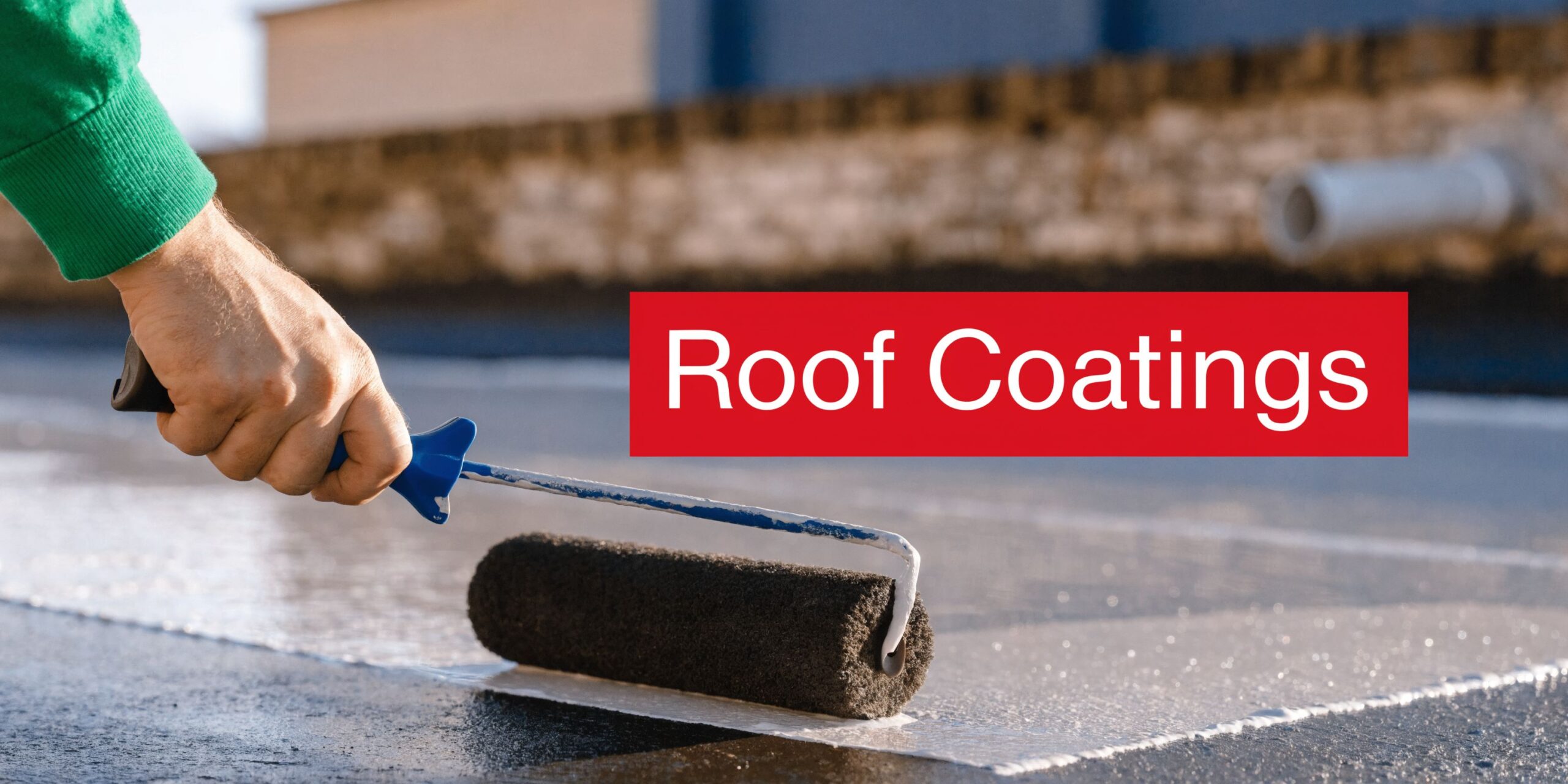 A person applying white protective roof coating to a flat roof surface using a paint roller.