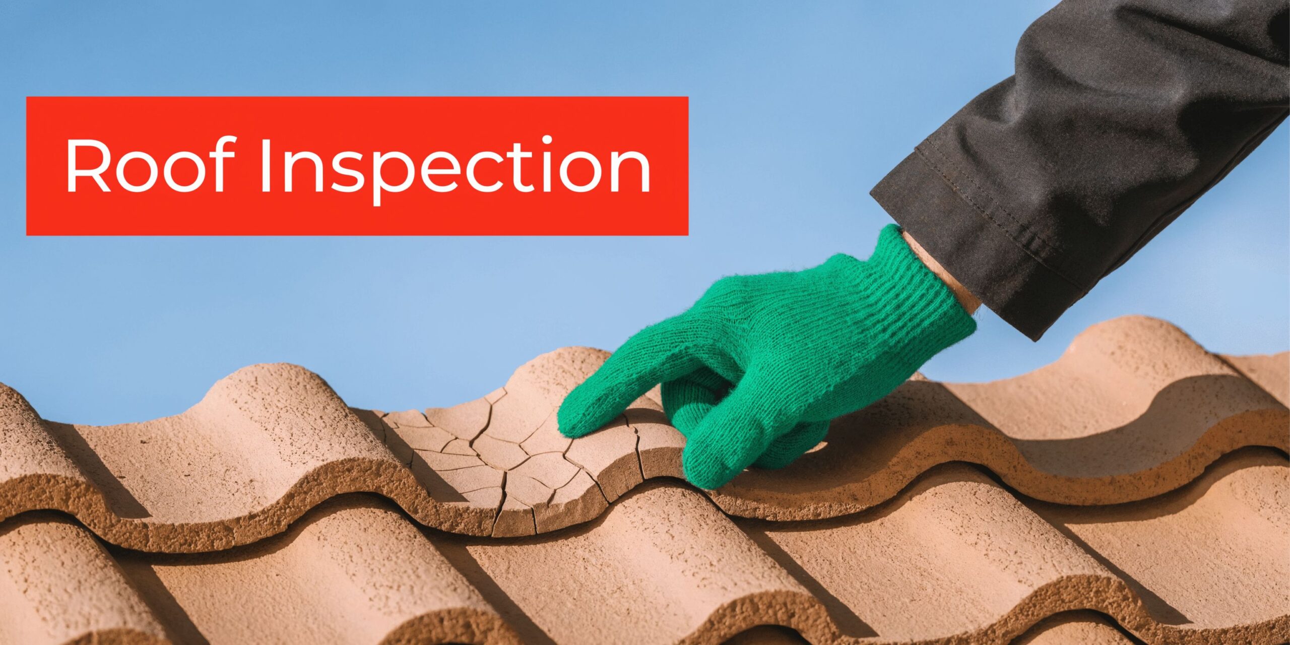 A gloved hand inspects a cracked, damaged roof tile, highlighting the need for a professional roof inspection.