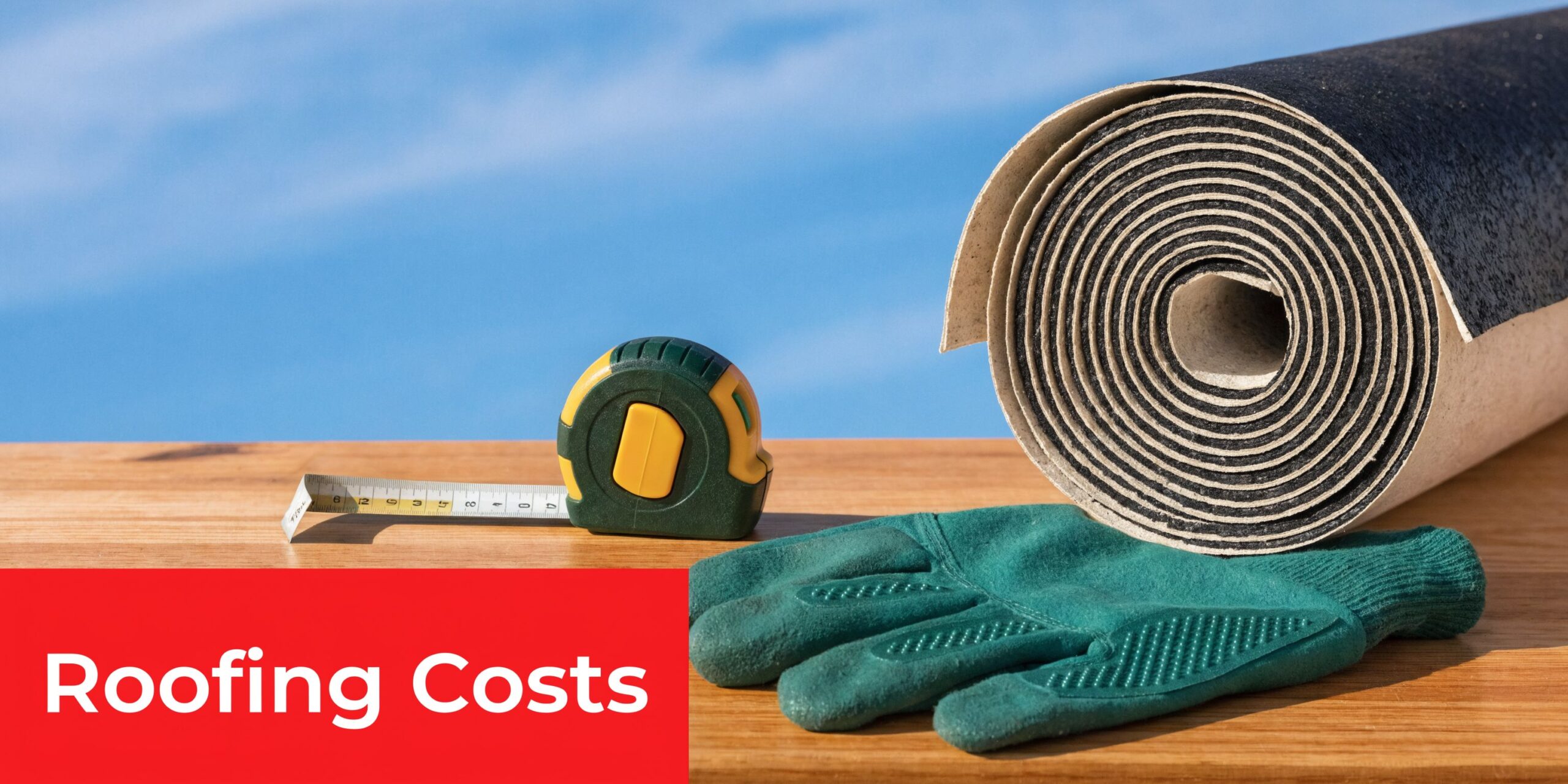 A roll of roofing material with a measuring tape and work gloves on a wooden surface.